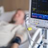 a man laying in a hospital bed next to a monitor